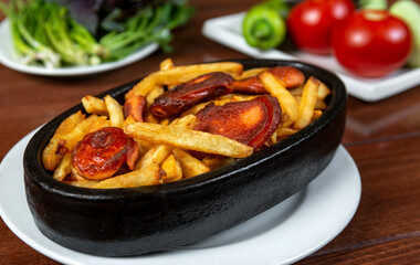 Frying pan with pieces fried sausage and potato