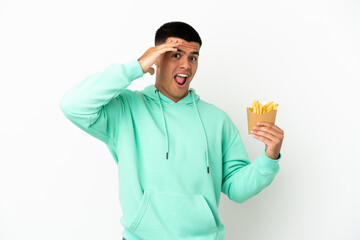 Young handsome man holding fried chips over isolated white background doing surprise gesture while looking to the side