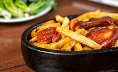Frying pan with pieces fried sausage and potato