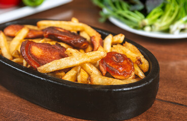 Frying pan with pieces fried sausage and potato