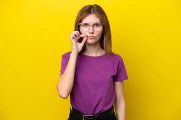 Young English woman isolated on yellow background showing a sign of silence gesture