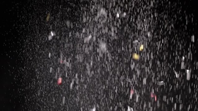 Stream of Falling Confetti, Dust Particles, and Snowfall on Black Background. Blurred abstract dynamic background of flying tinsel, snowflakes, white powder in cloudy mist smoke. Star rain, fireworks.