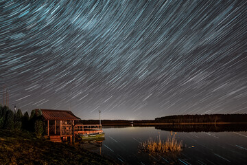 Startrails over the fishermans hut at the lake - 561217740