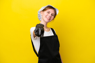 Young English fisherwoman isolated on yellow background pointing front with happy expression