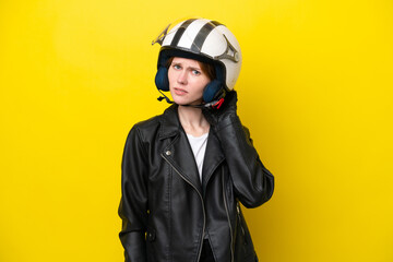 Young English woman with a motorcycle helmet isolated on yellow background having doubts