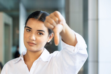 upset south asian, Indian woman office worker pointing rejecting thumb down hand gesture