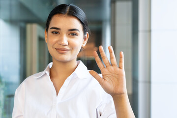 Happy smiling young south asian Indian office worker woman pointing up 5 fingers, showing number five, fifth place, 5 points gesture or stop and halt hand sign