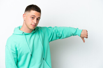 Young brazilian man isolated on white background showing thumb down with negative expression