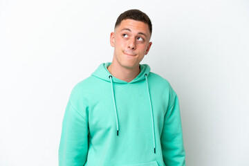 Young brazilian man isolated on white background having doubts while looking up