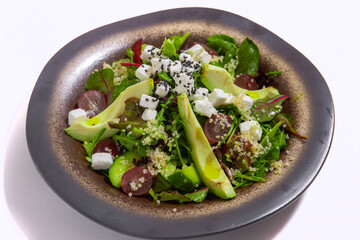 Bowl of vegetables salad with avocado on white background