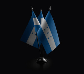 Small national flags of the Honduras on a black background.