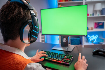 Unrecognizable gamer girl streaming video games with green screen mock-up display in gaming home studio. Player using professional computer wearing headset in neon light room. High quality photo