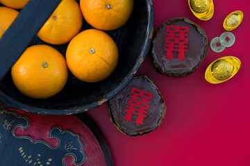 Oranges in basket, Chinese new year cake, gold ingots, coins isolated on red background, top view....