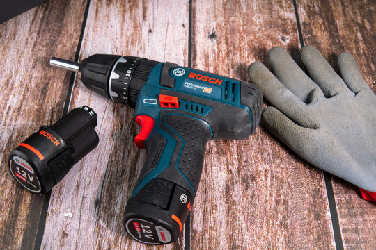 Bosch cordless screwdriver with glove and spare battery on a wooden floor for the hobby workshop
