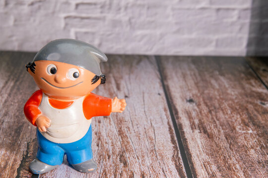 German Mainzelm&auml;nnchen Anton with cap reaches out his hand. Text space for own logo. Wooden floor and stone wall.