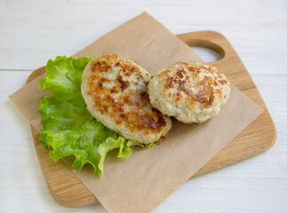 Delicious poultry cutlets. dietary product. Two cutlets lie on a wooden board with a lettuce leaf.