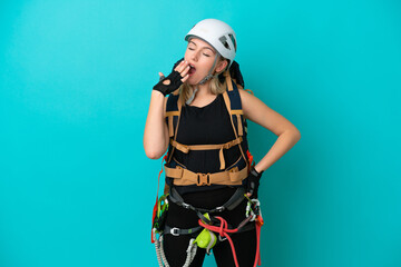 Fototapeta premium Young caucasian rock climber woman isolated on blue background yawning and covering wide open mouth with hand
