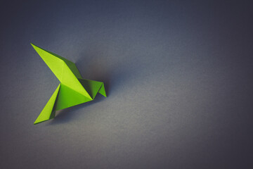 Green paper dove origami isolated on a grey background