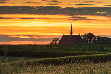 sunset over the field with church in the background - 561235992