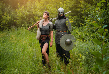 Young beautiful woman and man in armor, medieval warriors. A man in chain mail, a helmet with a...