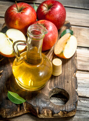 Apple cider vinegar with fresh red apples on a cutting Board.