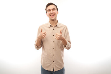 Fototapeta premium Young brunette man shows hand with thumbs up and smiles at the camera isolated on white background