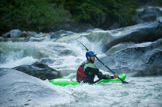 A whitewater kayaker sits in an eddy after running a series of rocky drops.
