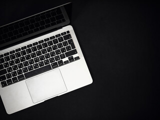 Modern gray metal laptop on a black surface. Remote work. Programming. hacker tool.