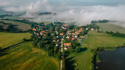 Aerial view of small village in fog.Top view of traditional housing estate in Czech. Looking straight down with a satellite image style.Houses from above, real estate concept.Country road urban scene