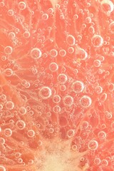 Slice of grapefruit in sparkling water. Grapefruit slice covered by bubbles in carbonated water. Grapefruit slice in water with bubbles