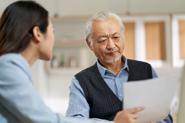 asian old man appears to be unconvinced while listening to a salesperson