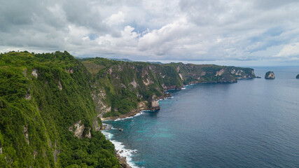 Fototapeta na wymiar Beautiful coastline aerial view from Saren Cliff Point. Clear water and rocks with cloudy sky. Nusa Penida, Indonesia.