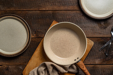 Empty pan and plates on dark wooden background. Overhead view