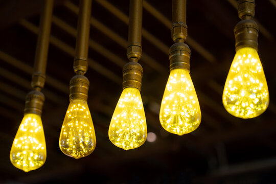 Glowing vintage light bulbs in coffee shop on black background