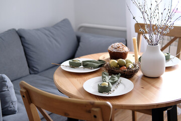 Beautiful Easter table with pastries, willow branches, eggs and candles.