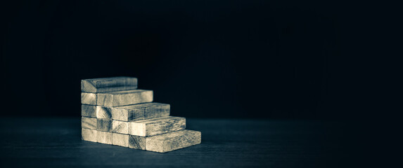 Wooden block tower stack in pyramid stair step with caution to prevent collapse or crash concepts...