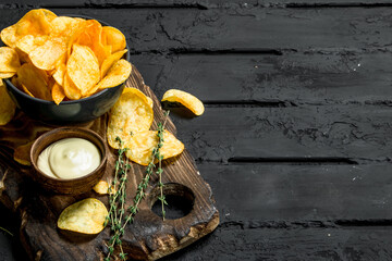 Potato chips in bowl with sauce and thyme.