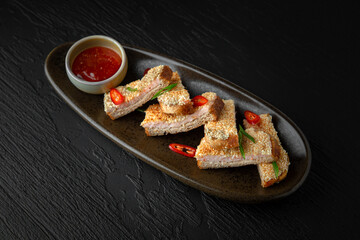 Shrimp toast in a ceramic plate on a dark textured background. Restaurant menu Isolated on black
