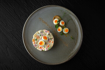 Olivier in a ceramic plate on a dark textured background. Restaurant menu Isolated on black