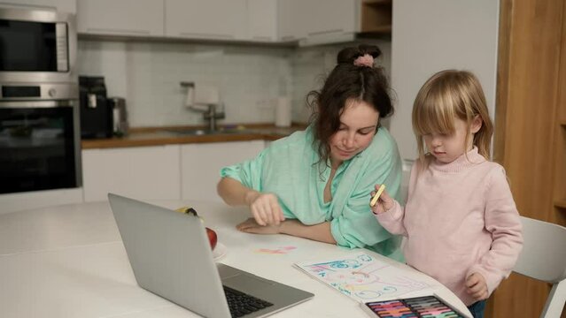 Beautiful mom helps her young daughter with her drawing