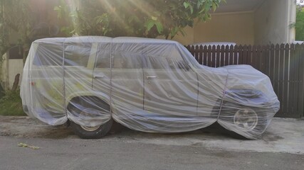 An old vintage SUV car cover with plastic to avoid from being rustic