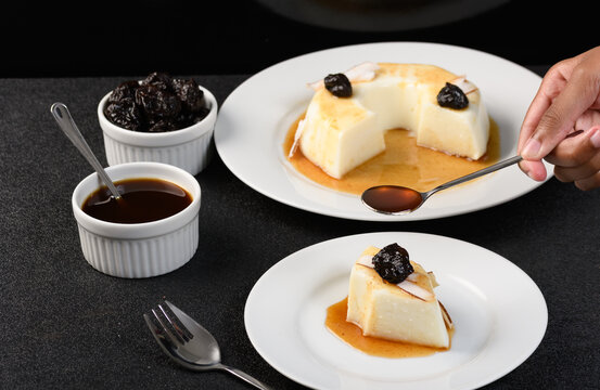  slice of coconut manjar on a white plate, plum syrup falling over the manjar 
