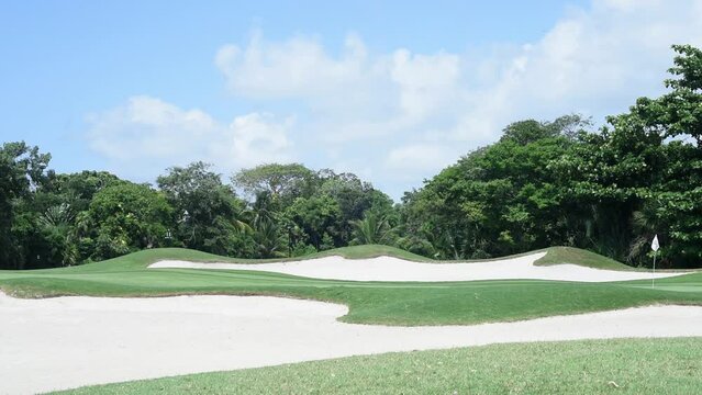 The beauty of a golf course in lush, tropical Mexico in HD footage shows a green protected by sand bunkers and surrounded by exotic plants. Perfect for sports-themed projects or travel promotions.