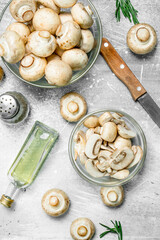 Sliced and whole mushrooms in bowl with knife.