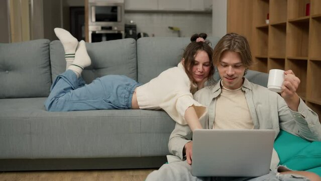 Young adult couple talking using laptop computer at home watching video