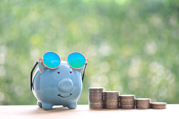 Stack of coins money and piggy bank on natural green background, Business investment and Real estate concept