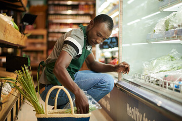 Supermarket worker checking food quality and putting expired products in basket