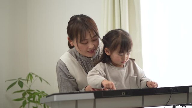 	ピアノを弾く練習をする親子
