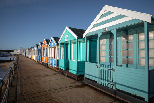 Colourful beach huts on the promonade by the pier in Southwold, Suffolk on a summers morning