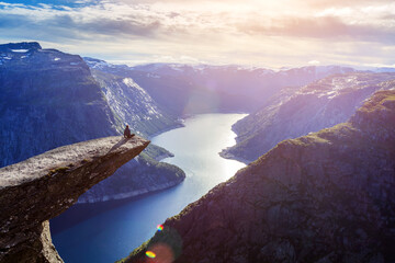Amazing nature view with Trolltunga and a man sitting on it at sunset. Location: Scandinavian mountains, Norway, Odda. - 561270917